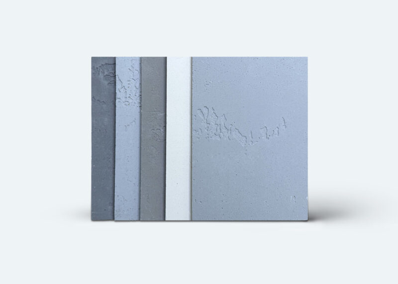 Fünf Musterplatten in Betonoptik zeigen verschiedene Grautöne für fugenlose Wand- und Bodengestaltung im Badezimmer.