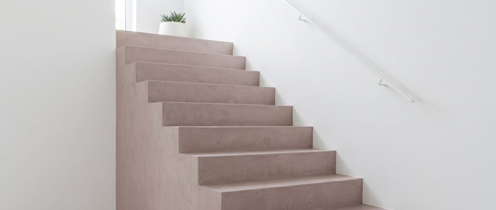 Fugenlose COLORIAMO-Betonoptik-Treppe mit elegantem Design und minimalistischer Wandgestaltung in hellen Tönen. | © COLORIAMO